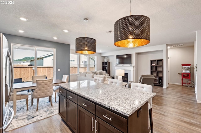 1939 Branch Creek Dr, Longview, WA 98632 - kitchen featuring freestanding refrigerator, a textured ceiling, light wood-style flooring, dark brown cabinets, and hanging light fixtures