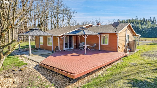 back of house with a chimney, roof with shingles, a yard, and a deck