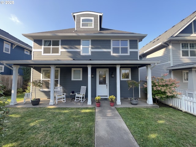 traditional style home featuring a front lawn, fence, and covered porch