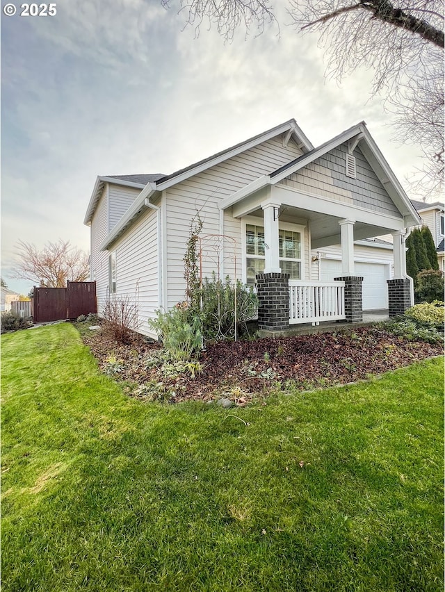 view of front of property featuring a porch, a garage, and a front lawn