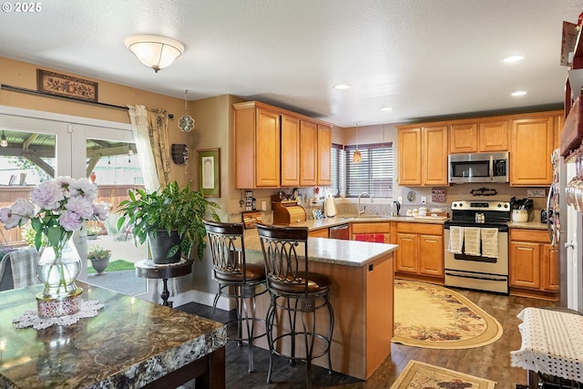 216 Churchill Downs St, Albany, OR 97322 - kitchen with appliances with stainless steel finishes, a peninsula, a kitchen bar, dark wood-style floors, and recessed lighting