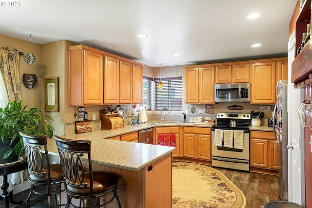 216 Churchill Downs St, Albany, OR 97322 - kitchen featuring appliances with stainless steel finishes, a peninsula, decorative light fixtures, a breakfast bar area, and wood finished floors