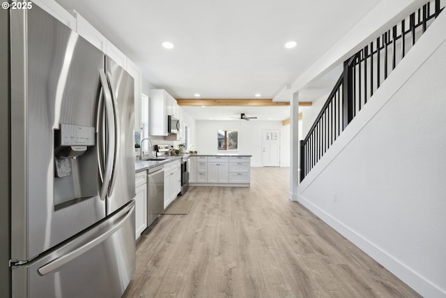 kitchen featuring appliances with stainless steel finishes, a peninsula, light wood-style floors, recessed lighting, and white cabinetry