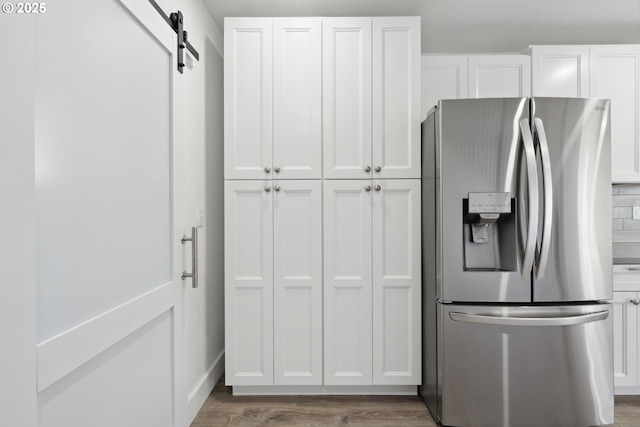 kitchen with stainless steel fridge with ice dispenser, white cabinetry, wood finished floors, and a barn door