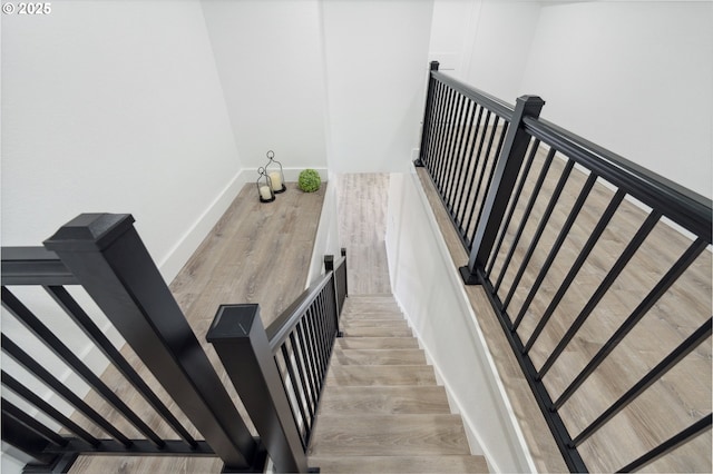 stairs featuring wood finished floors and baseboards