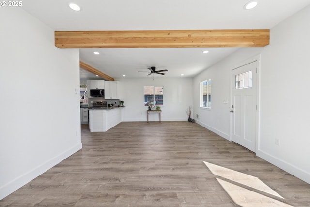 unfurnished living room featuring recessed lighting, beam ceiling, ceiling fan, baseboards, and light wood-style flooring