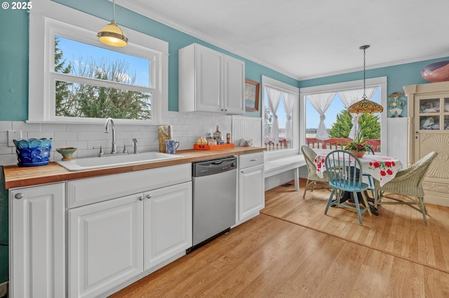 kitchen featuring decorative light fixtures, a sink, stainless steel dishwasher, and white cabinetry