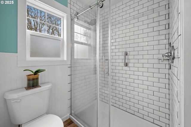 bathroom with wainscoting, a shower stall, and toilet