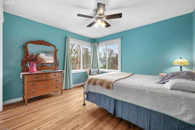 bedroom with light wood-type flooring, a ceiling fan, and baseboards