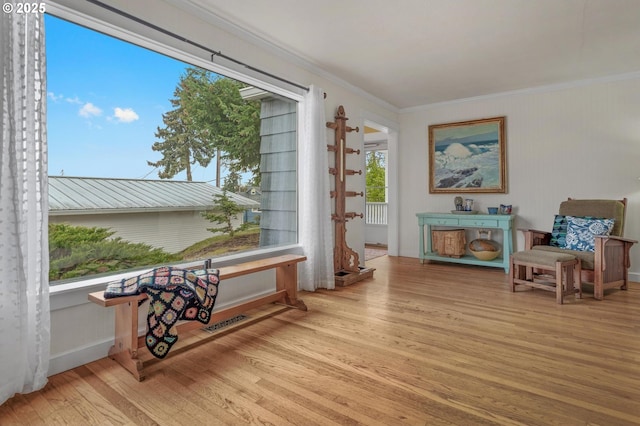 sitting room featuring ornamental molding, light wood-style flooring, and visible vents