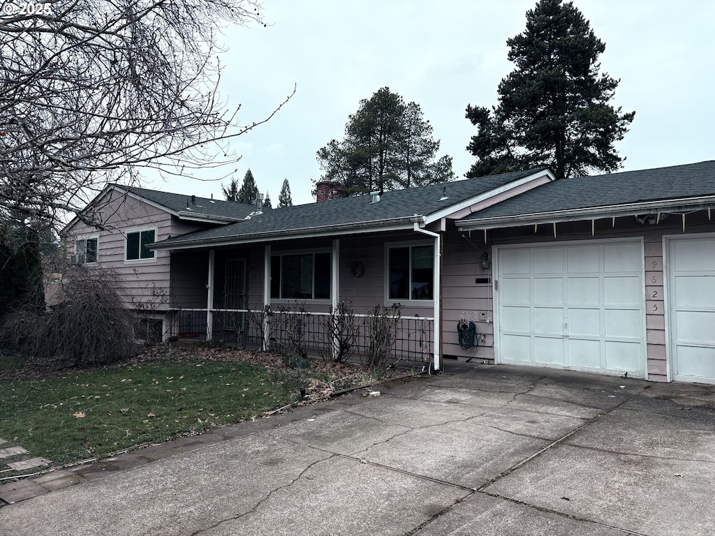 split level home with a porch, a chimney, driveway, and an attached garage