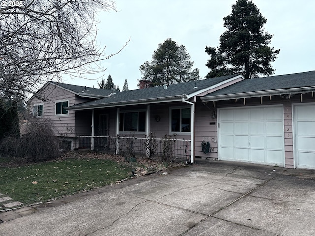 split level home with an attached garage, covered porch, driveway, and a chimney