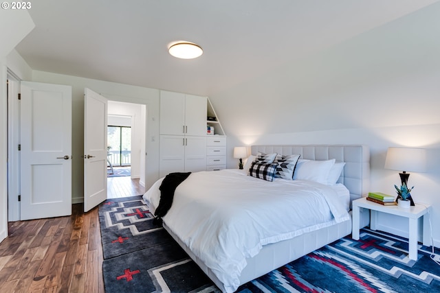 bedroom with lofted ceiling and dark wood-style floors