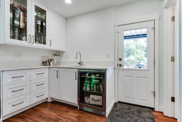 bar featuring wet bar, dark wood-type flooring, beverage cooler, and a sink