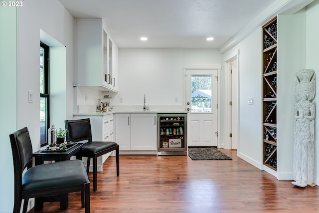 bar featuring beverage cooler, wood finished floors, wet bar, recessed lighting, and a sink