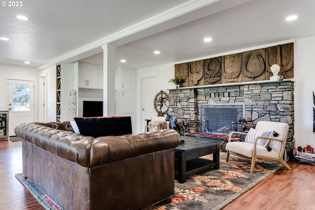 living area featuring a stone fireplace, recessed lighting, and wood finished floors