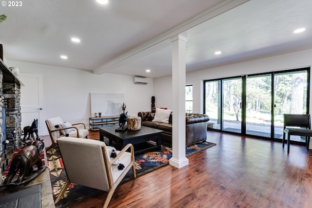 living room with decorative columns, an AC wall unit, and a healthy amount of sunlight