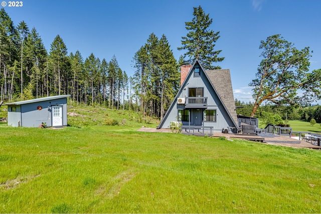 rear view of property with a chimney, a wooden deck, and a yard