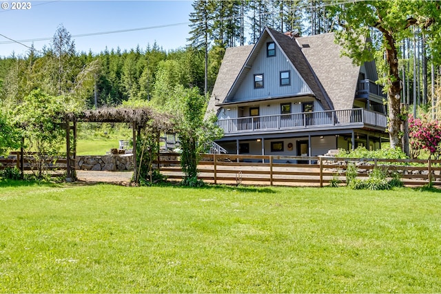 rear view of property featuring a yard, roof with shingles, and fence