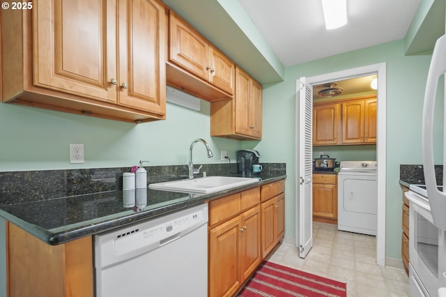 kitchen with range, washer / clothes dryer, freestanding refrigerator, white dishwasher, and a sink