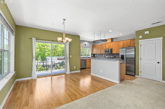 8844 NE Brentford Way, Hillsboro, OR 97006 - kitchen featuring stainless steel appliances, a chandelier, a kitchen island, light wood-style flooring, and decorative backsplash