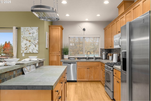 8844 NE Brentford Way, Hillsboro, OR 97006 - kitchen with stainless steel appliances, a sink, recessed lighting, light wood-style floors, and decorative backsplash
