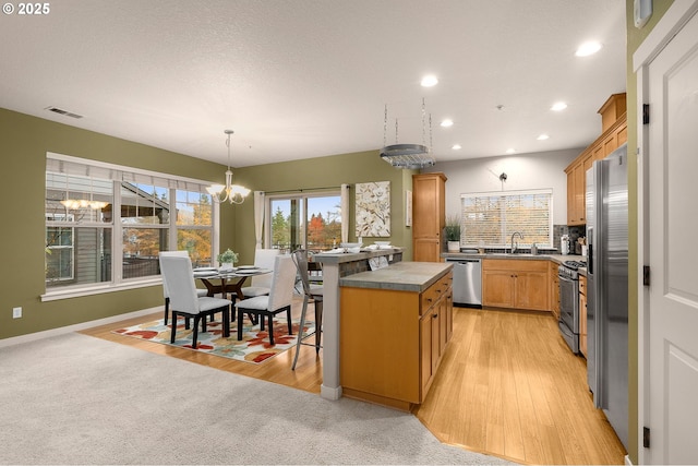 8844 NE Brentford Way, Hillsboro, OR 97006 - kitchen with stainless steel appliances, a chandelier, recessed lighting, a kitchen island, and light wood-style floors