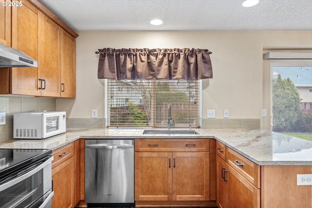 2462 NE 11th Ave, Hillsboro, OR 97124 - kitchen featuring stainless steel appliances, a sink, a peninsula, light stone counters, and brown cabinets