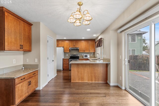 2462 NE 11th Ave, Hillsboro, OR 97124 - kitchen with white appliances, under cabinet range hood, dark wood-type flooring, brown cabinets, and recessed lighting