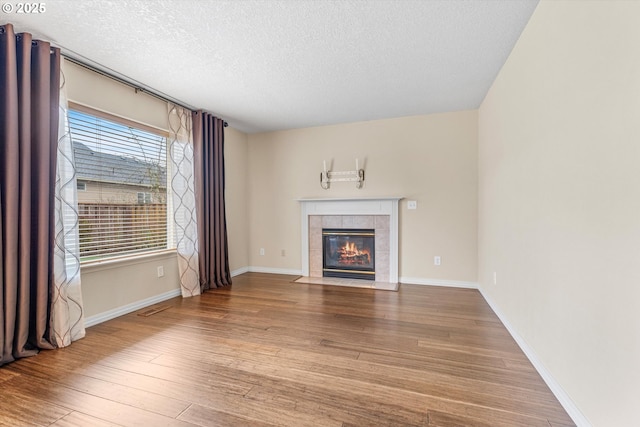2462 NE 11th Ave, Hillsboro, OR 97124 - unfurnished living room with a textured ceiling, wood finished floors, a tiled fireplace, and baseboards