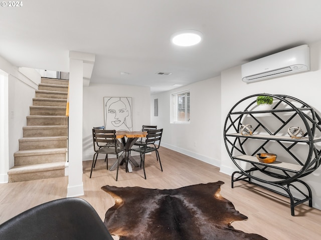 dining room featuring light wood-type flooring and a wall unit AC