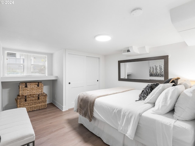 bedroom with light hardwood / wood-style floors and a closet