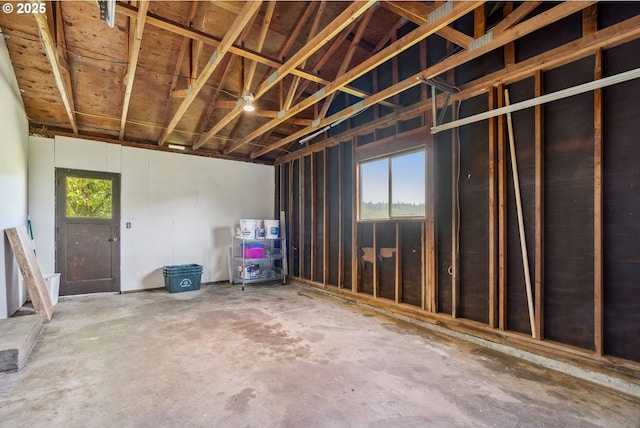misc room with a garage and unfinished concrete flooring