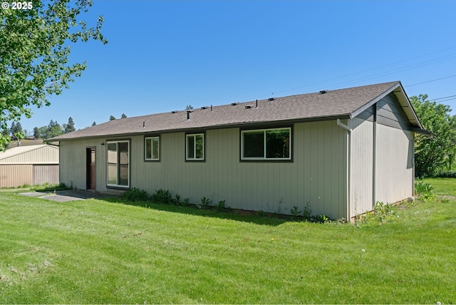 back of property with a lawn and roof with shingles