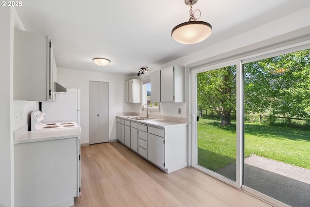 kitchen featuring electric stove, extractor fan, light countertops, a sink, and light wood-style flooring