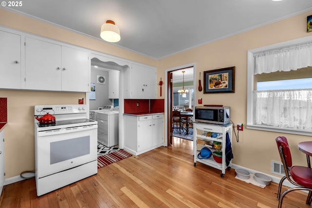 1815 SE 97th Ave, Vancouver, WA 98664 - kitchen with white electric range oven, stainless steel microwave, washer and clothes dryer, light wood-type flooring, and plenty of natural light