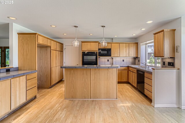 7471 SW Woodbury Loop, Wilsonville, OR 97070 - kitchen featuring black appliances, a center island, light wood finished floors, hanging light fixtures, and recessed lighting