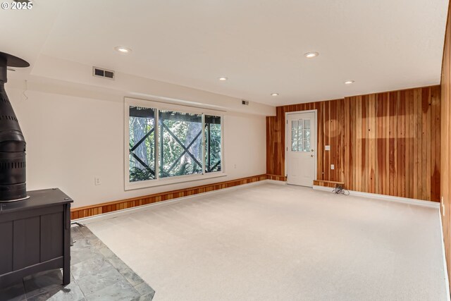 7471 SW Woodbury Loop, Wilsonville, OR 97070 - unfurnished living room featuring a wood stove, wooden walls, recessed lighting, and carpet floors
