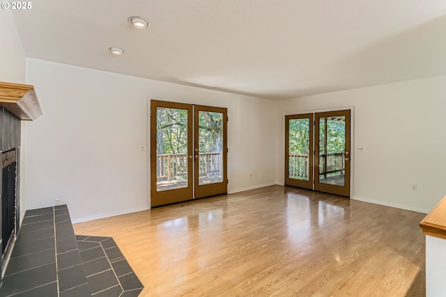 7471 SW Woodbury Loop, Wilsonville, OR 97070 - unfurnished living room featuring a tile fireplace, plenty of natural light, wood finished floors, french doors, and recessed lighting