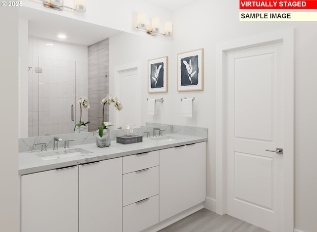 full bathroom with a stall shower, double vanity, and a sink