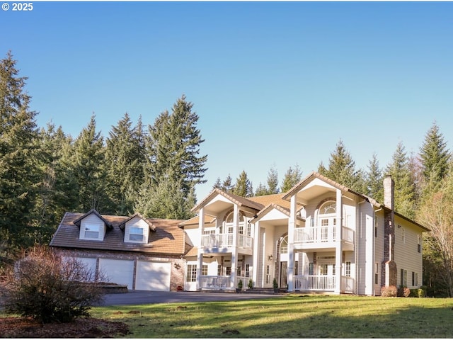 view of front of home featuring a garage, driveway, a balcony, and a front lawn