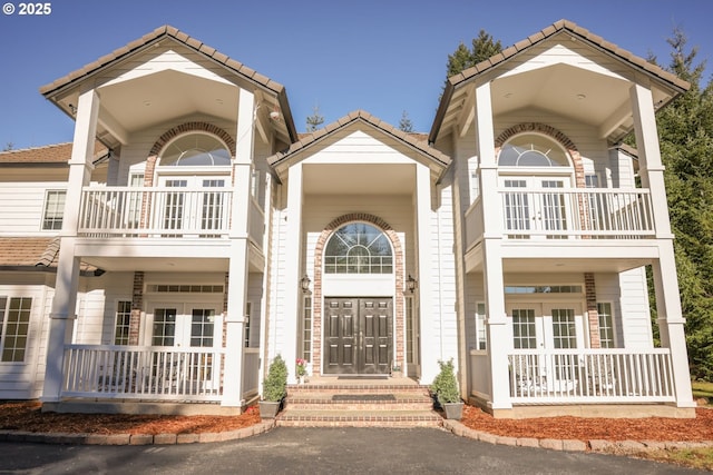 view of front facade featuring a tile roof, french doors, and covered porch