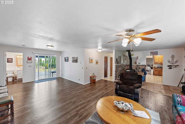 91256 Cape Arago Hwy, Coos Bay, OR 97420 - living area with a wood stove, wood finished floors, a ceiling fan, and baseboards