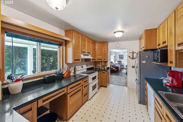 91256 Cape Arago Hwy, Coos Bay, OR 97420 - kitchen with white appliances, under cabinet range hood, dark countertops, light flooring, and a sink
