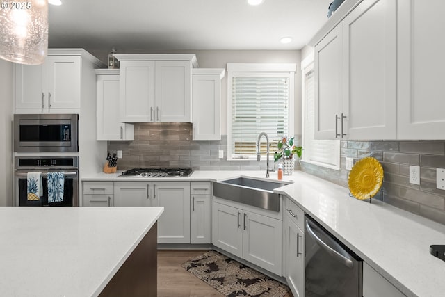 kitchen with stainless steel appliances, hanging light fixtures, sink, and white cabinets