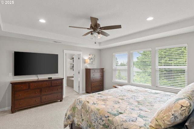 carpeted bedroom featuring a raised ceiling, ceiling fan, and ensuite bathroom