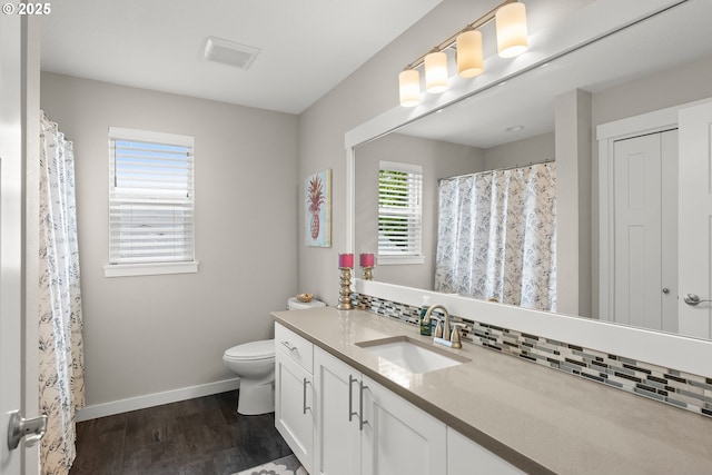 bathroom featuring vanity, toilet, hardwood / wood-style floors, and decorative backsplash