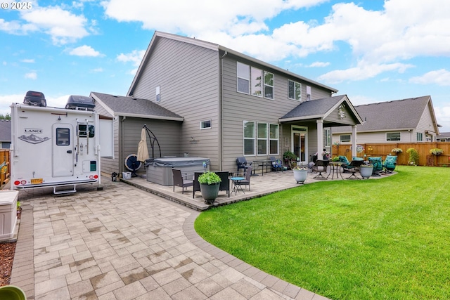 rear view of house with a yard, a hot tub, and a patio area