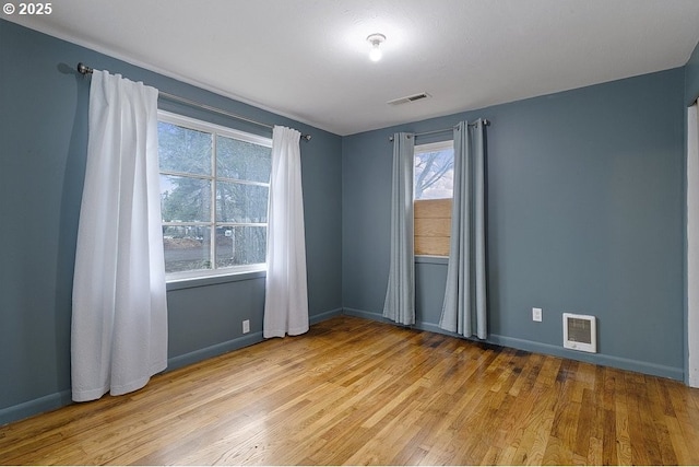 unfurnished room featuring baseboards, visible vents, and light wood-style floors