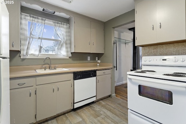 kitchen with light wood-style floors, white appliances, light countertops, and a sink